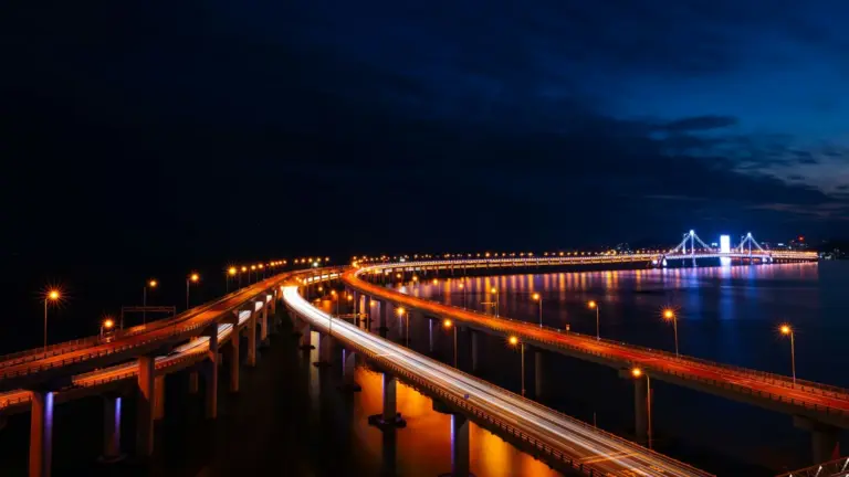 Illuminated bridge at night with light trails